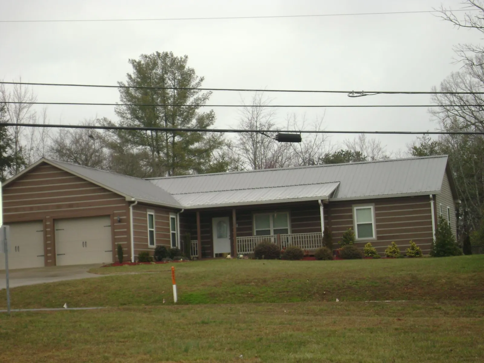 Gray metal roof on a log sided ranch home with a front porch in Taunton